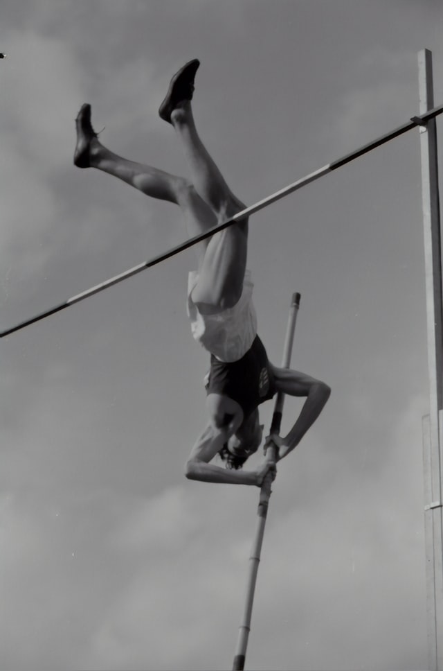 Play on words raising above the bar with a pole vaulter